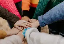 person in red sweater holding babys hand