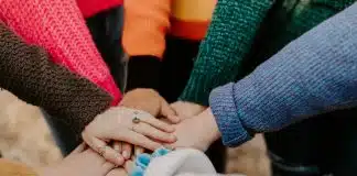 person in red sweater holding babys hand